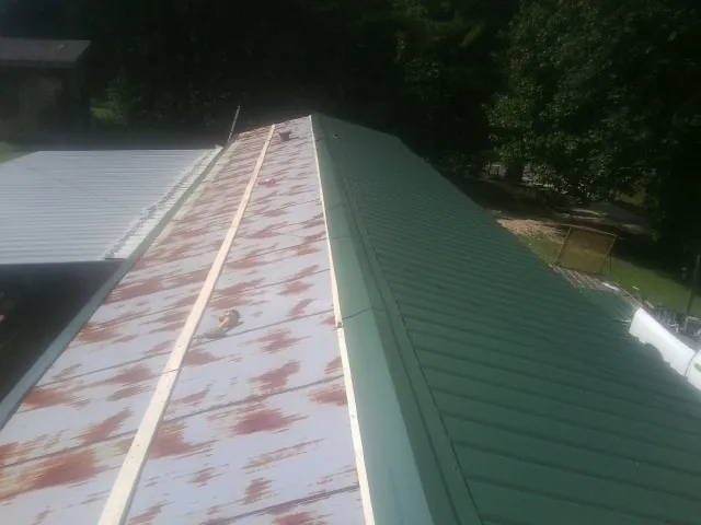 Old rusted panels beside newly installed green metal roofing — Wind Damage Roof Repair by Roofing Brothers in Kenesaw