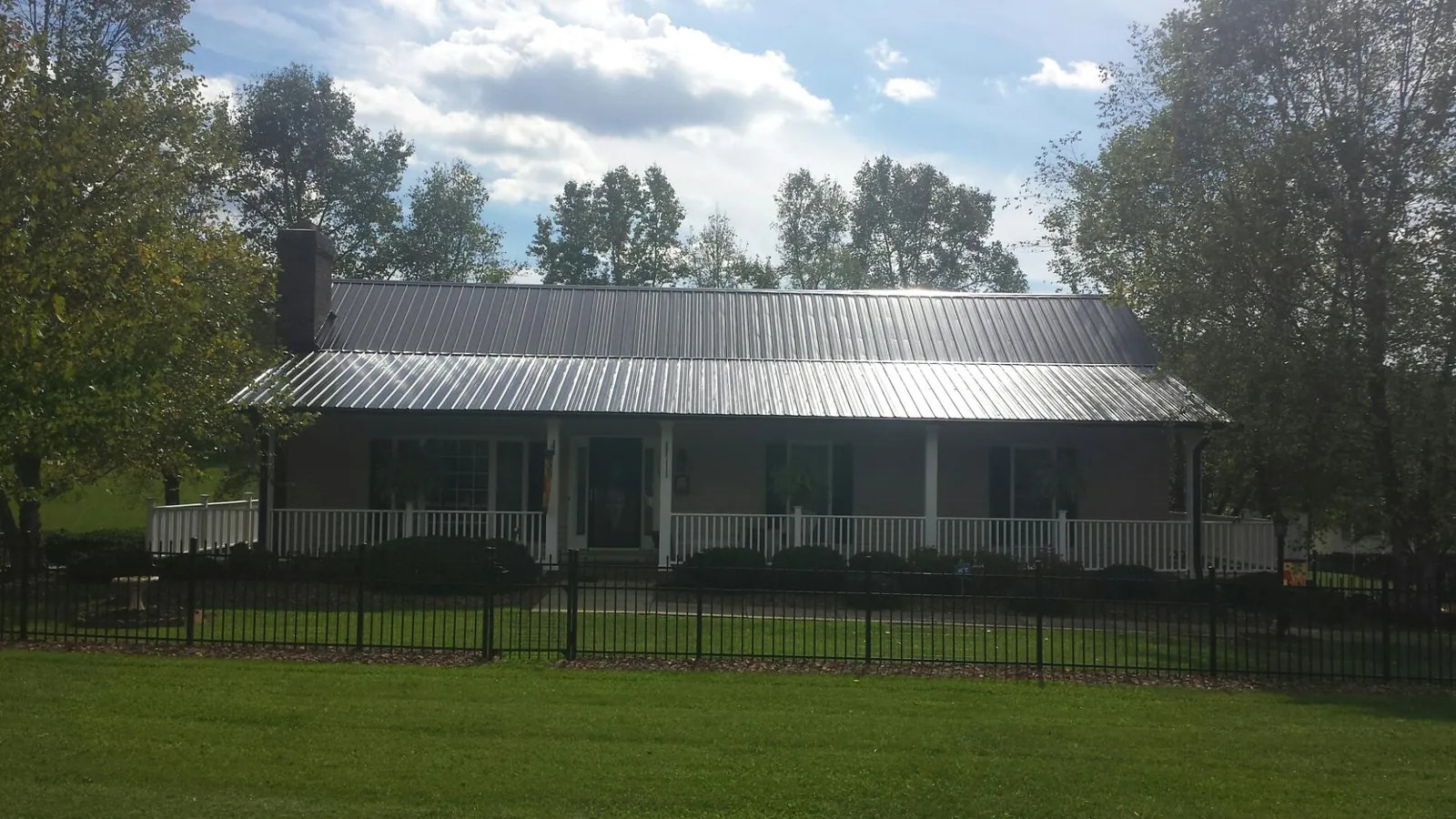 Gray metal roof on a brick ranch with a full width front porch — Gutter Guard Installation work by our crew in Kenesaw