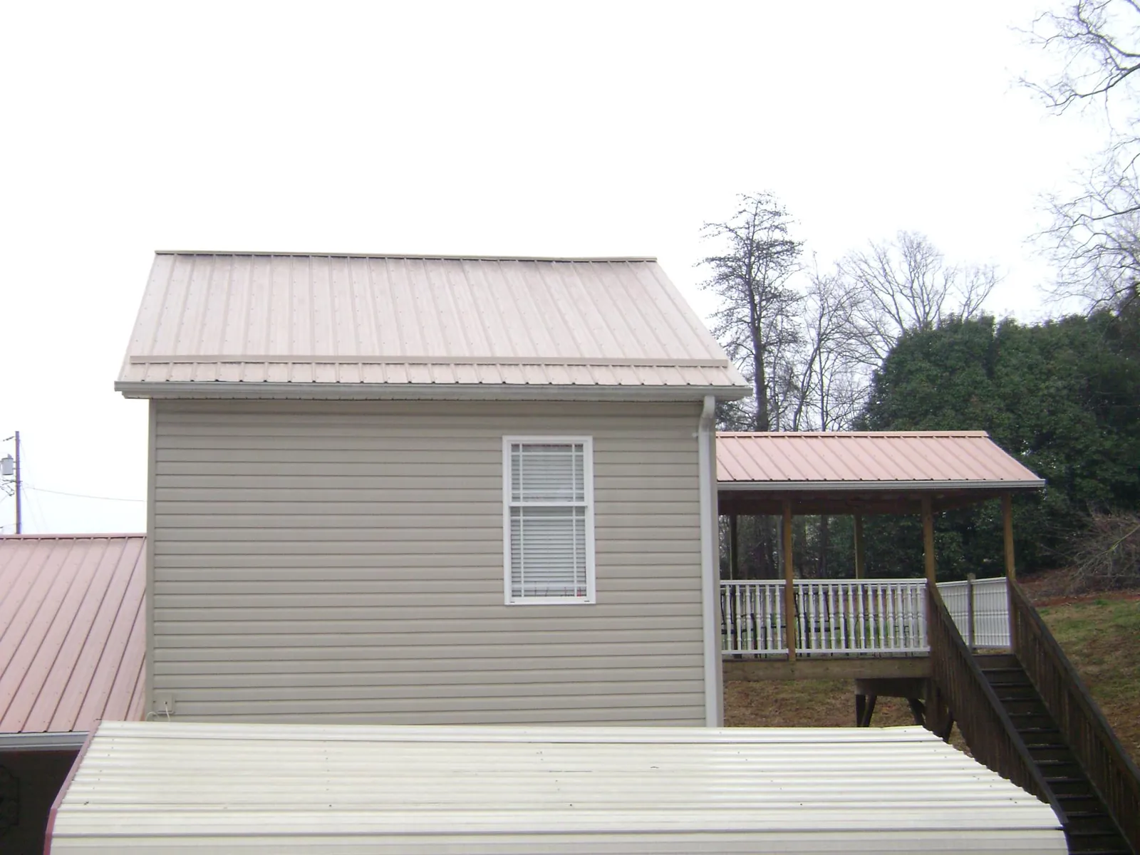 Tan metal roofs on a two story addition and attached porch, from a Roof Replacement job in Kenesaw