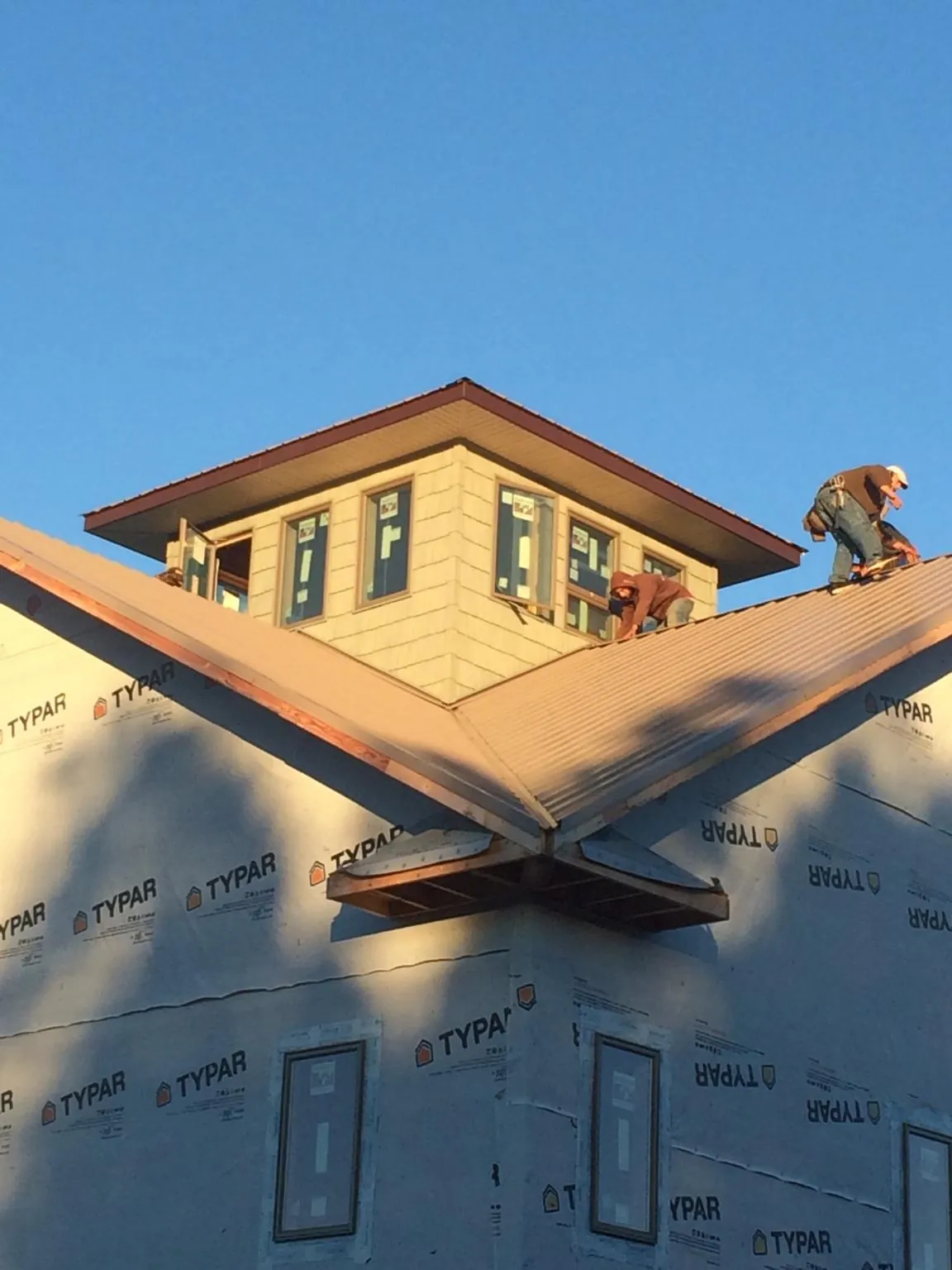 Roofers working around a rooftop cupola on a new metal roof at sunset — Roof Waterproofing in Kenesaw by Roofing Brothers